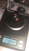 Photo of the black opal gemstone on a digital scale showing a weight of 12.40 carats.