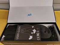 Photo of black and grey heated socks folded in box with user guide visible.