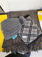 Set of winter accessories including brown scarf, grey Billabong toque, and grey plaid neck warmer laid out on yellow surface.