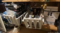 Photo of shelf with bins containing multiple packages of batteries, vacuum storage bags, and 4-pack box of fake CCTV cameras for mounting