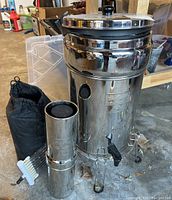 Main Berkey stainless steel gravity water filter system with upper and lower chambers on stand, two filter housings at side, drawstring bag and brush
