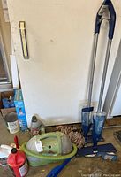View of all items: Bissell spot cleaner, two Bona floor cleaning mops, a Bona cleaning solution bottle, and Bona duster cloth on floor next to garage wall