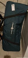 Full view of dark green carrying bag with Disc-O-Bed logo and black straps, lying on floor