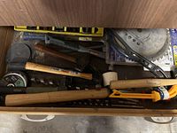 Top drawer with assorted hand tools including hammers, mallets, pry bar, saw blades, and drill bits.