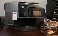 Photo showing the HP OfficeJet Pro 8625 printer with multiple ink cartridges beside it on the table.