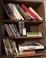 Books on shelving with titles relating to hunting, arrowheads, and general fiction or reference books visible.