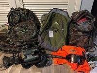 Overview of three backpacks, walkie-talkies, GPS, binoculars, shirt and goggles.