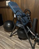 Photo of Ironman memory foam inversion table showing blue padded backrest, black frame, and exercise balls.