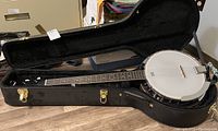 Full view of banjo seated in open black hard shell case showing overall condition