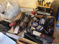 Overview photo showing Bauer cordless drill, screwdriver set in display holder, assorted flashlights including magnetic lights, and nailing tool on workbench