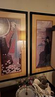 Pair of framed vertical art prints in dark wood with beige matting, featuring Asian inspired figures and calligraphy.