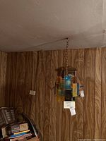 Chandelier hanging from ceiling in basement room with wood paneling walls, showing multiple colored stained glass panels and chain attachment.