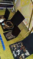 Four black velvet display boxes containing various earrings, necklaces and bracelets on a patterned floor.