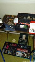 Wide view of multiple jewelry trays on table showing assorted rings, bracelets, earrings