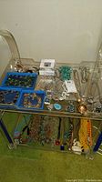 Overall display of assorted jewelry laid out on shelves including necklaces, beaded items, and boxed sets.