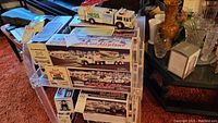 Wide view of top shelf showing loose white Hess tanker truck on clear display shelf with two large boxed sets beneath