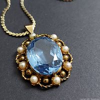 Front view of pendant on chain showing aquamarine and seed pearls
