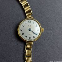 Front view of watch face showing silver dial, Arabic numerals, ‘Leda’ logo and winding crown
