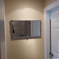 Front view of rectangular beveled mirror with decorative metal frame mounted on wall