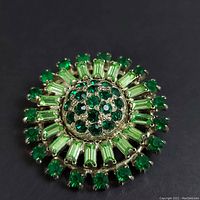 Close up image showing front detail of round green Austrian crystal brooch with two shades of green crystals set in silver-tone metal.