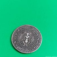 Coin obverse showing central emblem/deity and Tamil inscriptions