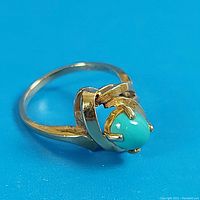 Side view of ring showing turquoise cabochon and swirl prong setting