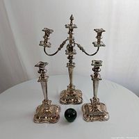 Overview of set with green apple for scale, showing three-branch candelabra and two stick candlesticks
