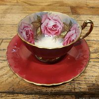 Angled view of teacup and saucer showing red exterior finish and interior floral pattern