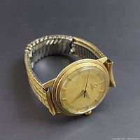 Angled view of gold-filled Omega watch and expansion band on black background