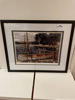 Full view of framed Tom Thomson print titled The Canoe showing landscape with canoe by lake and trees