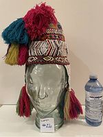 Front view of the vintage Tibetan headdress displayed on a glass head, showing detailed beadwork and colorful tassels.
