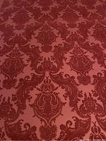 Close-up photo showing the intricate damask pattern in red velvet on wallpaper.