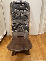 Front view of carved wooden birthing chair showing three sections of animal figures (lions and tiger).