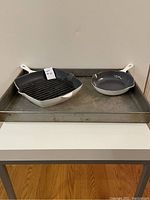 Overview of all items: square grill pan and round frying pan displayed on industrial sheet pan