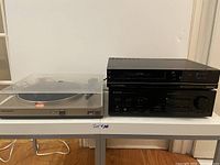 Photo showing Marantz TT240 turntable and Pioneer A-441 stereo amplifier placed side by side on a table, to display overall items offered in the lot.