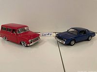 Front view of red 1957 Suburban and blue 1987 Buick Regal diecast cars side by side.