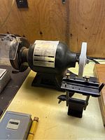 Side view of the 6 inch Brico bench grinder showing the motor label, protective shield, and tool rest.