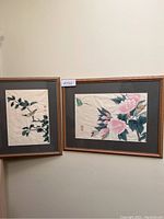 Pair of framed paintings hung on a wall, showing both artworks side by side with visible matting and wooden frames