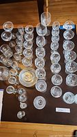 Overhead photo showing multiple rows of glassware arranged by type and size, also showing clear glass plates in center.