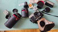 Overview of camera with multiple lens cases and accessories spread on table, showing camera body, lenses, and cases