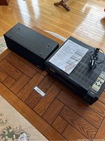 Onkyo AV receiver with Energy center channel speaker on wood floor, with instruction manual on top.