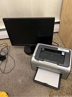 Monitor and printer together on carpet floor, including cables