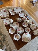 Overhead view of assorted plates, cups, saucers, bowls, sugar, creamer, platters and tea/coffee service arranged on table