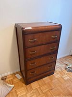 Full front angle view of vintage walnut dresser with all drawers closed showing wood grain and brass handles.