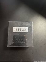 Front view of unopened box labeled 'SHEGLAM Baked Glow Setting Powder NET WT 5.5 g / 0.19 oz'.