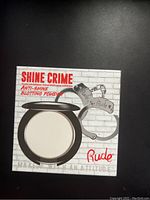 Photo of unopened Rude Shine Crime Anti-Shine Blotting Powder compact in black case with outer packaging showing graphics and branding