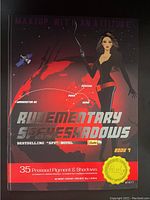 Photo of unopened RUDE Cosmetics Rudementary Spyeshadows eyeshadow palette showing front cover with 35 pressed pigment shadows text, spy theme, and illustration of woman with globe and city names.
