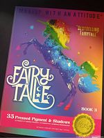 Photo of the unopened Rude Cosmetics Fairy Tale Book 3 eyeshadow palette with colorful unicorn design and 35 pressed pigment and shadows