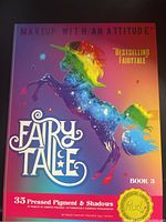 Closed Rude Cosmetics Fairy Tale Book 3 eyeshadow palette showing colorful unicorn artwork and product info.