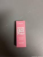 Photo of the front of the pink box of Amor Us Perfecting Face Primer showing brand and product name